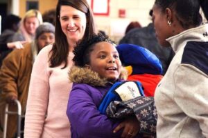 Kids accept coats from volunteers and donators at the BeWarm event